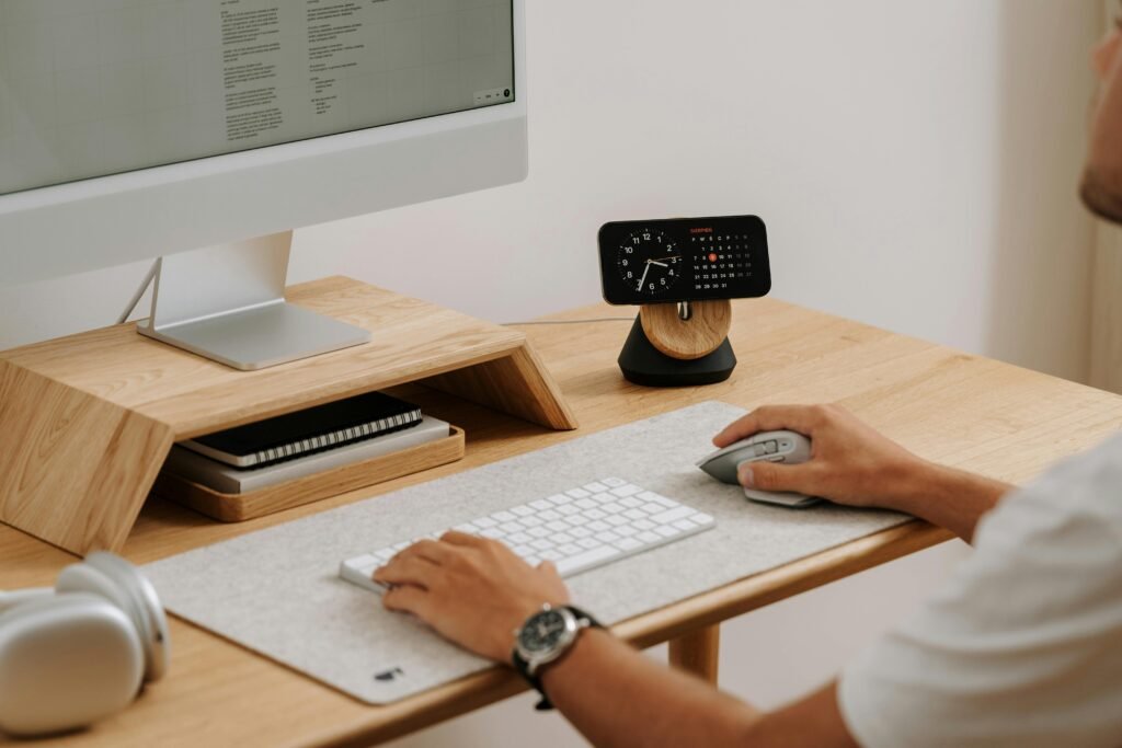 pexels-photo-19238352-19238352 A clean and modern desk setup featuring a computer, clock, and accessories in a home office.